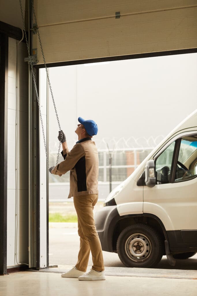 man pulling down garage door using chain